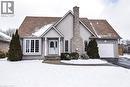 View of front of house with driveway, a chimney, and a garage