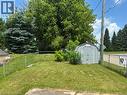 Fenced yard featuring a gray storage shed and mature trees