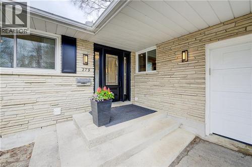 View of exterior entry with a porch, a garage, and brick siding