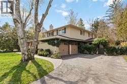 Stucco-finish exterior with dark brown trim accents, two attached garage doors, and established landscaping