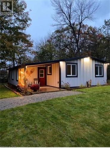The property features a white exterior with black trim, a covered porch with an inviting red door, and a well-maintained lawn