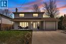 Traditional-style home featuring stucco siding, an attached garage, a chimney, driveway, and a front lawn