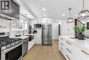 Kitchen with stainless steel appliances, white cabinetry, and light stone counters