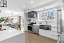 Kitchen with stainless steel appliances, tasteful backsplash, light wood finished floors, light stone countertops, and hanging lights