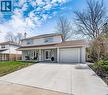 Traditional home featuring stucco siding, an attached garage, a porch, a chimney, and driveway