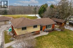 View of front facade with a front lawn, roof with shingles, brick siding, and a patio area