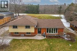 View of front facade with brick siding, a patio, a shingled roof, and a wooded view