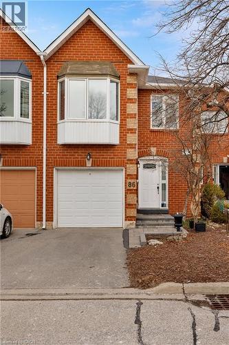 View of front of house featuring driveway, an attached garage, and brick siding