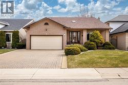 Single story home featuring brick siding, a garage, decorative driveway, and roof with shingles