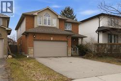 Traditional-style home featuring driveway, brick siding, a shingled roof, and an attached garage