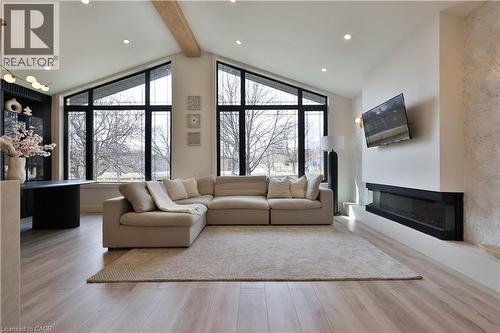 Living area with light wood-style flooring, a glass covered fireplace, and recessed lighting