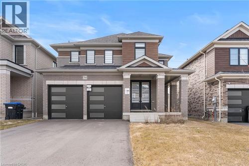 View of front facade featuring driveway, a front yard, an attached garage, and brick siding