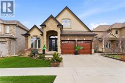 French country home with stucco siding, stone siding, driveway, a front lawn, and a garage