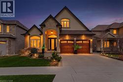 French country inspired facade featuring stone siding, stucco siding, concrete driveway, a yard, and an attached garage