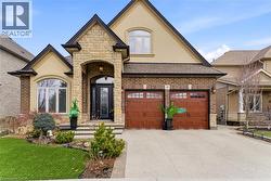 French provincial home with stone siding, concrete driveway, stucco siding, a front yard, and roof with shingles