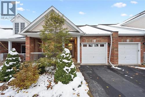 View of front of house featuring asphalt driveway, a garage, brick siding, and a porch