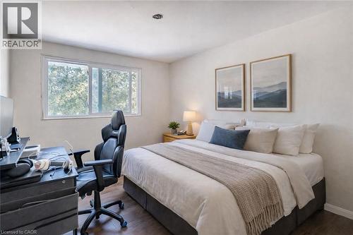 Bedroom featuring wood-finish flooring, white painted walls, a large window, and a recessed ceiling light
