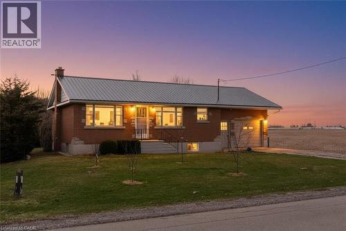 View of front of home featuring a front yard, a metal roof, driveway, and an attached garage