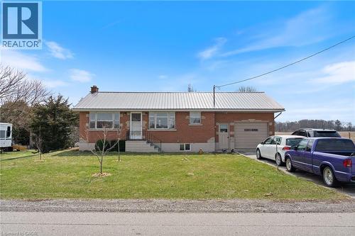 Ranch-style home with a metal roof, a garage, brick siding, and a front lawn