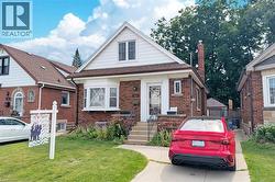 Brick-front residence featuring a prominent bay window, white siding accents, and a brown shingle roof