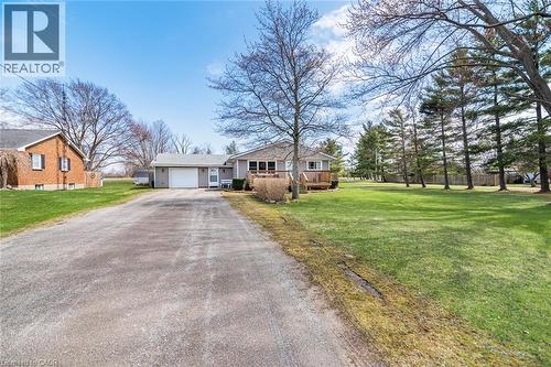 View of front of property featuring a front yard, driveway, an attached garage, and a wooden deck