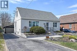 View of front of house featuring a shingled roof, an outbuilding, stucco siding, and a detached garage