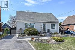 View of front of property featuring a shingled roof, an outbuilding, stucco siding, and a front lawn