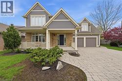 Two-story residence featuring a brick and siding facade, covered front porch with white railing, and a paver driveway