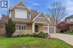 Traditional-style home featuring a covered front porch, brick and siding exterior, multi-pane windows, an integrated two-car garage, and a paver driveway