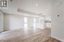 The open concept living area features light wood-style flooring, white walls, recessed lighting, and large windows providing ample natural light