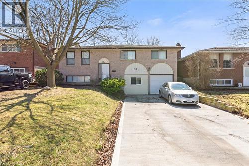 Bi-level home with driveway, a front yard, brick siding, and an attached garage