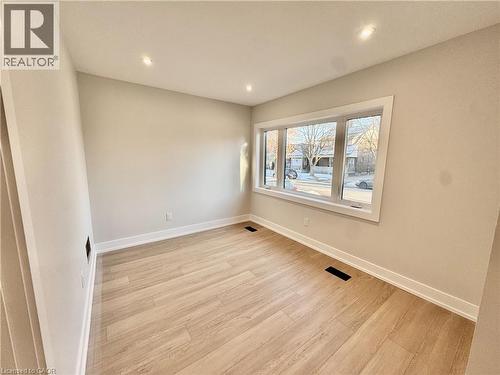 This room offers light-toned flooring, white baseboards, and a window providing a view of the street