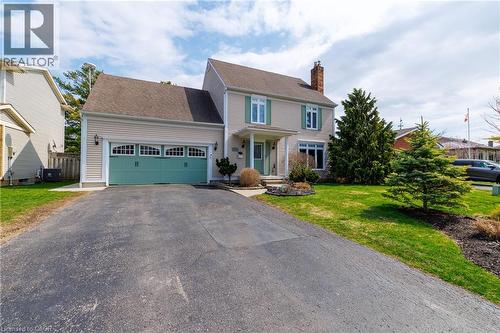 The property features a two-story exterior with light-colored siding, a prominent front entrance, and a two-car garage with a teal door