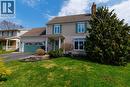 The property features a beige siding exterior with green shutters and a complementary green garage door, set against a green lawn