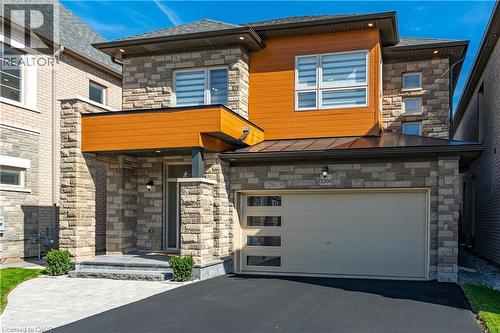 The property features a stone and wood facade with a paved driveway and a garage with horizontal window inserts