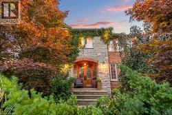 The property features a stone and brick exterior, with mature trees and extensive landscaping surrounding the entrance
