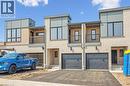 The property features a modern exterior with light-colored brick, dark grey garage doors, and contemporary windows