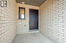 The property features light-colored brick exterior walls, a dark-paneled entry door, and a window with a dark frame