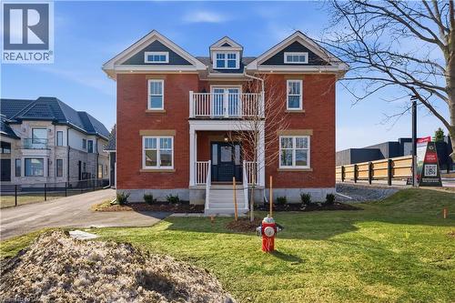 The property features a red brick exterior with white trim, a dark roof, and a front balcony with white railings