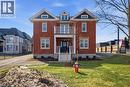 The property features a red brick exterior with white trim, a dark roof, and a front balcony with white railings