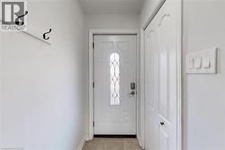 Entryway featuring a white door with decorative glass inserts, light tile flooring, and a white closet door with black handles