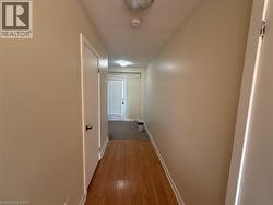 Hallway featuring wood-finish flooring, light-toned walls, recessed lighting, and a white interior door with black hardware