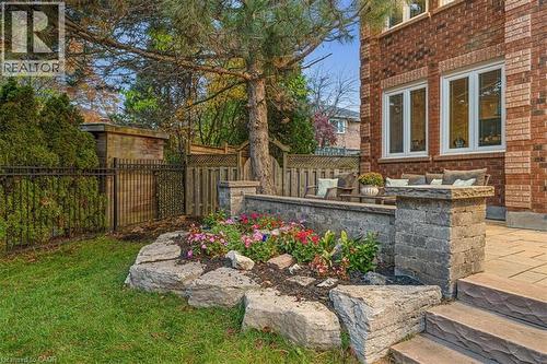 Stone paver patio featuring a retaining wall with integrated plantings, tiered stone steps, and a brick exterior