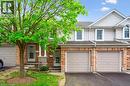 Townhome / multi-family property with driveway, a garage, a shingled roof, and brick siding