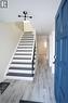 Entryway featuring a bold blue front door, wood-finish flooring, a contemporary black light fixture, and a staircase with patterned risers and black treads
