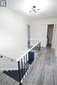 Stairwell featuring wrought iron and wood railing, wood-finish flooring, and a modern ceiling light fixture