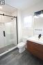 Modern bathroom featuring a glass-enclosed shower with subway tile surround, floating wood-finish vanity with integrated sink, contemporary black fixtures, and plank-style floor tiling