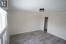 Room with wood-finish flooring, white baseboards, and neutral wall paint