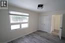 Room featuring wood-finish flooring, a double-pane window with blinds, and white baseboards
