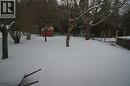 Expansive backyard featuring mature trees, a red shed with white trim, and a chain-link fence